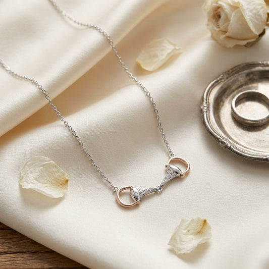 Necklace with a rose gold and silver clasp on a soft beige fabric background