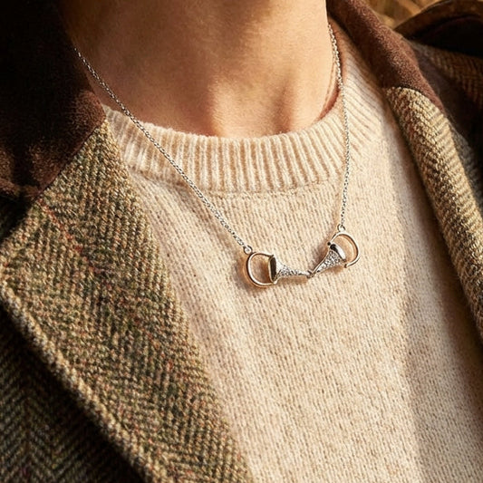 Person wearing a necklace with a horse bit pendant in a rustic setting