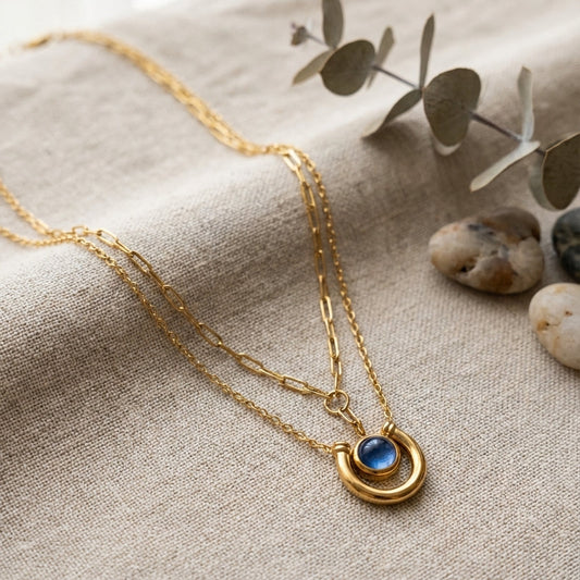 Double horseshoe pendant necklace with gold horseshoe charm and blue gemstone