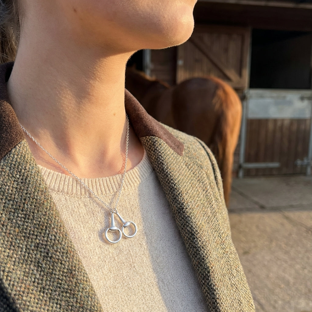 Person wearing a necklace with a horse pendant in an outdoor setting